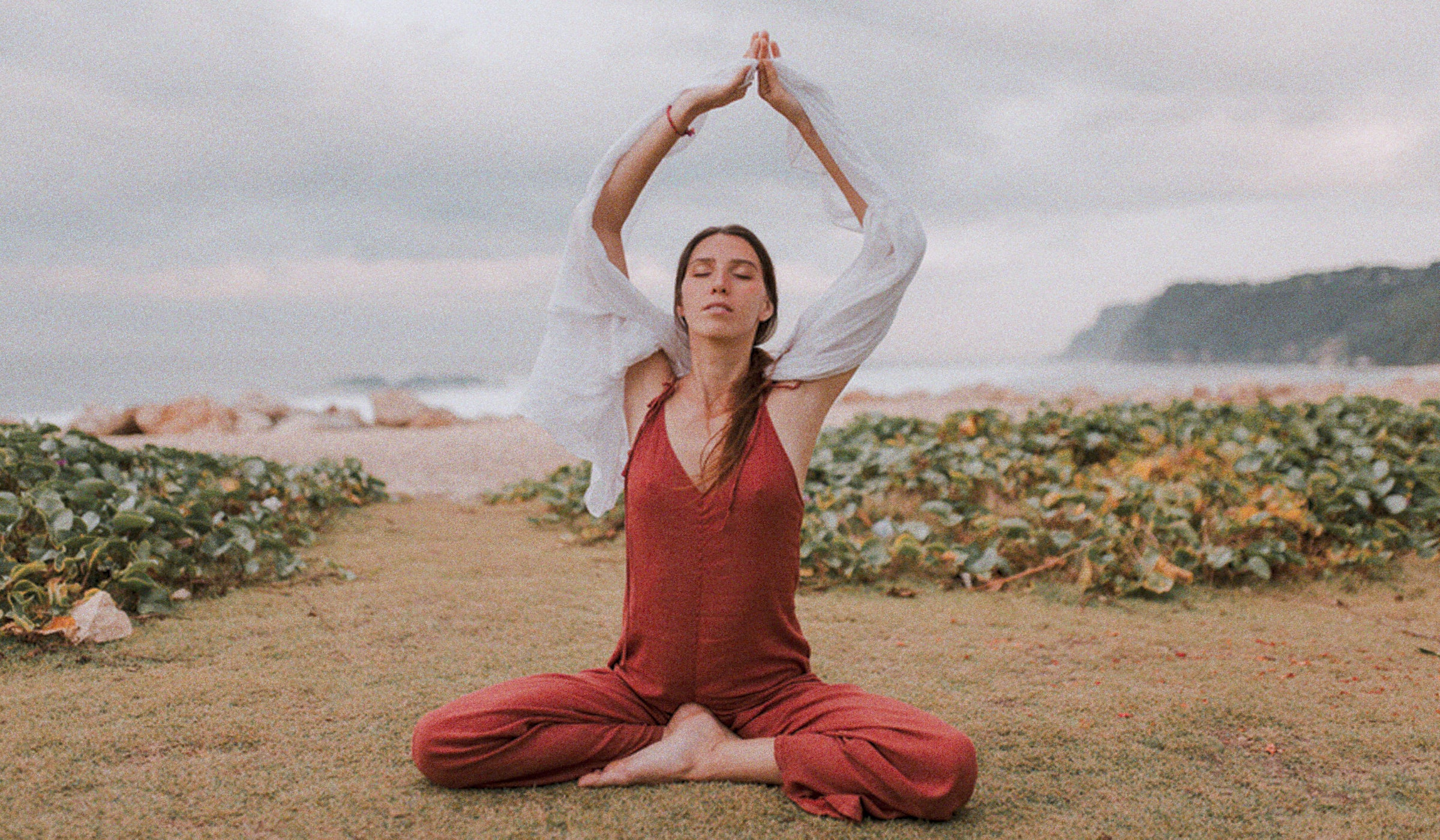 Serene moment: A brunette woman meditating on the California seashore, embracing tranquility by the sea.